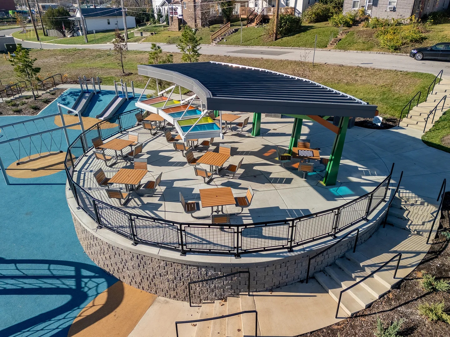 Aerial view of the Brentwood Pavilion at Destination Playground in Brentwood Park, featuring colorful light panels, shaded seating for 44, and nearby playground.